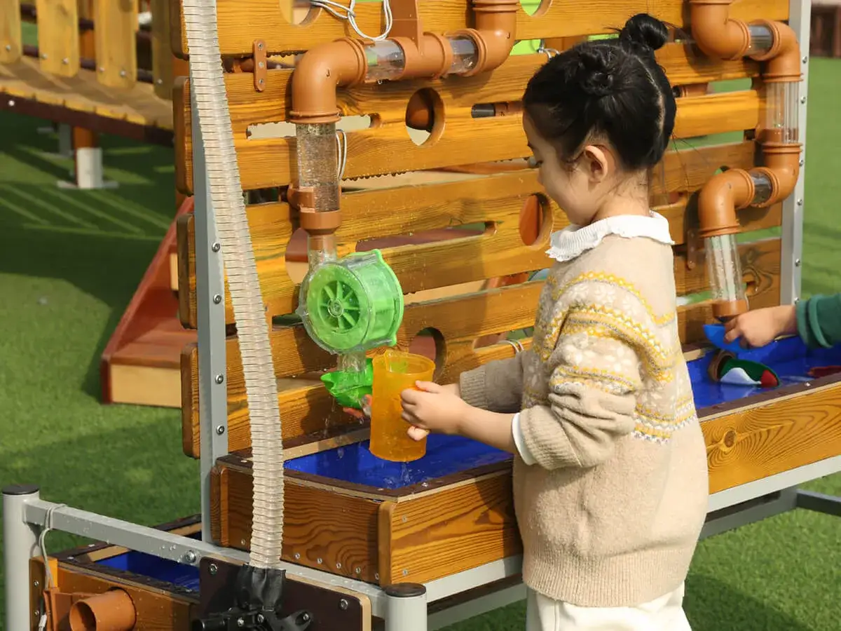 Ein Mädchen spielt mit einer Wasserwand, ein toller Spaß bei den Sommerspielen für Kinder.