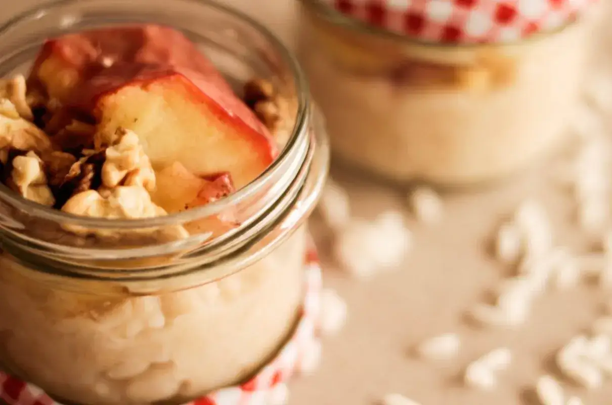 Pyszny pudding ryżowy z cynamonem, jabłkami i orzechami włoskimi w słoiczku. Idealny deser na chłodne dni.