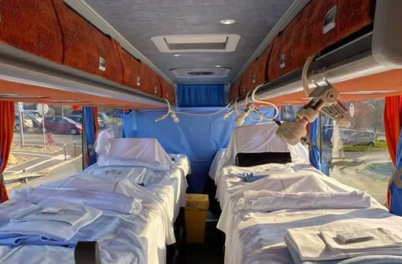 Intérieur d'un bus aménagé avec des lits, rappelant une installation de type
