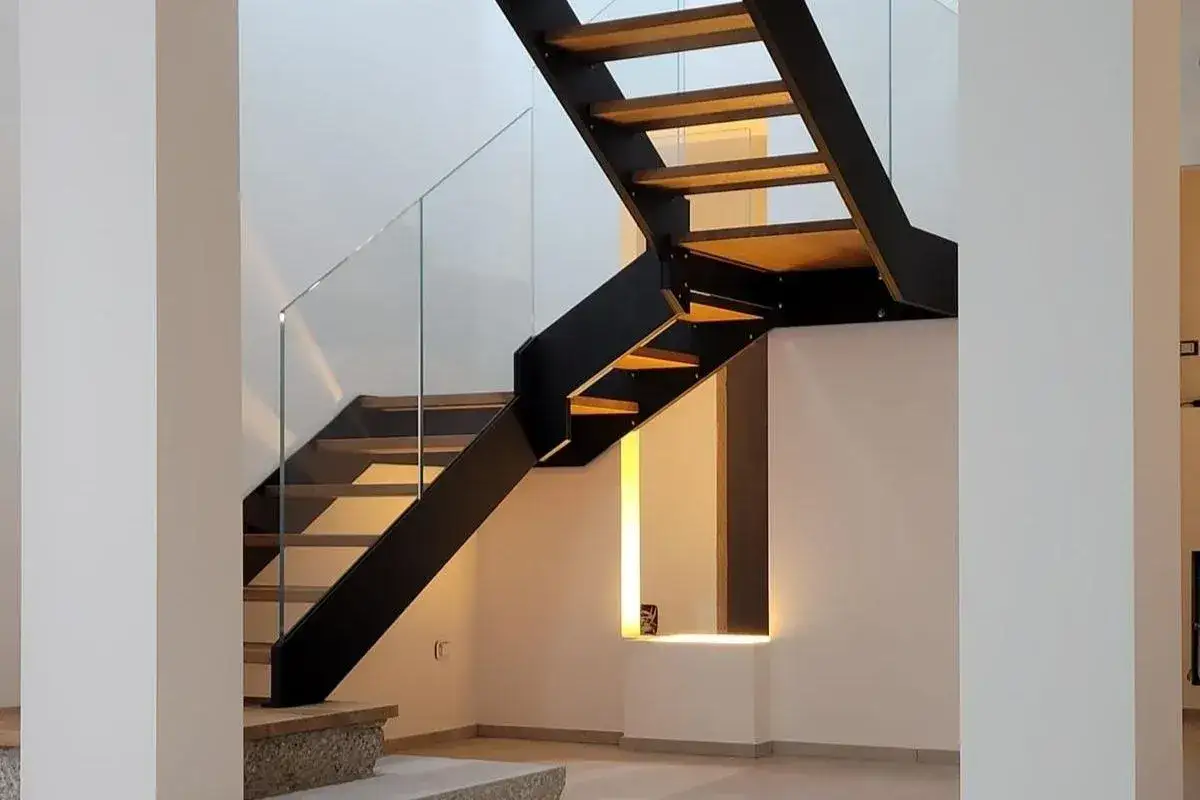 Scala interna con parapetto in vetro e gradini in legno. Il design moderno della scala interna &egrave; esaltato dal parapetto in vetro e dalla struttura in metallo nero.