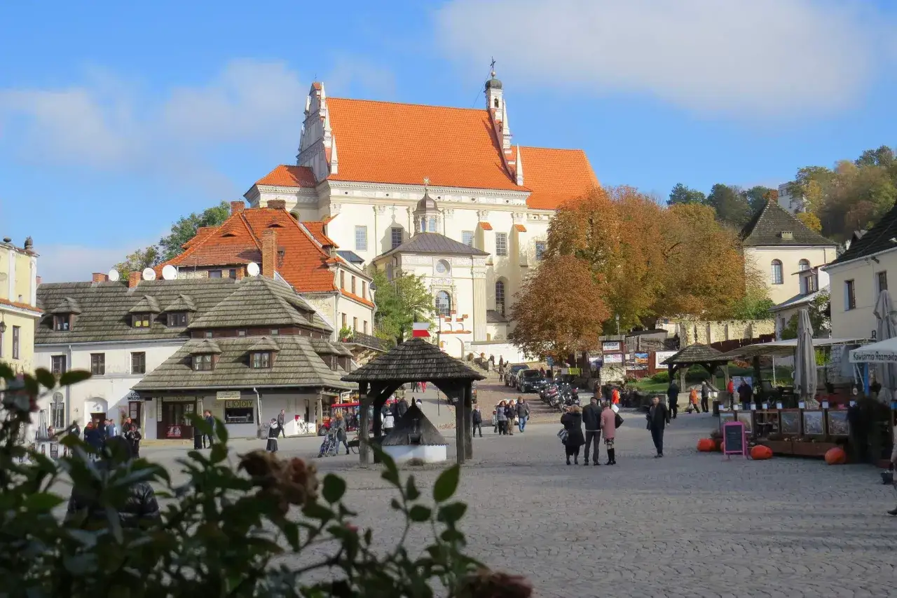 Rynek w Kazimierzu Dolnym, jedno z **ciekawe miejsca 150 km od Warszawy**. Piękna architektura, jesienne drzewa i ludzie spacerujący po bruku.