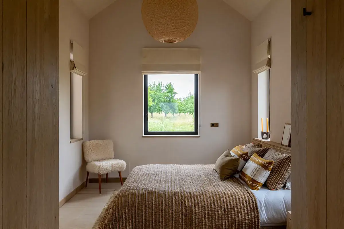 Une chambre cabine cosy avec un lit douillet, une chaise en fausse fourrure et une vue sur la nature par la fenêtre.