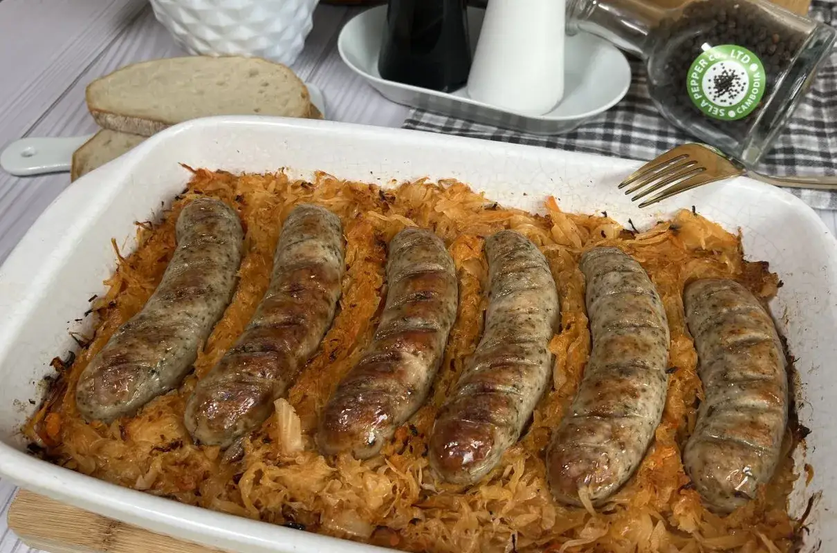Pyszna biała kiełbasa z kapustą kiszoną zapieczona w naczyniu. Idealne danie na obiad, które zachwyci smakiem.