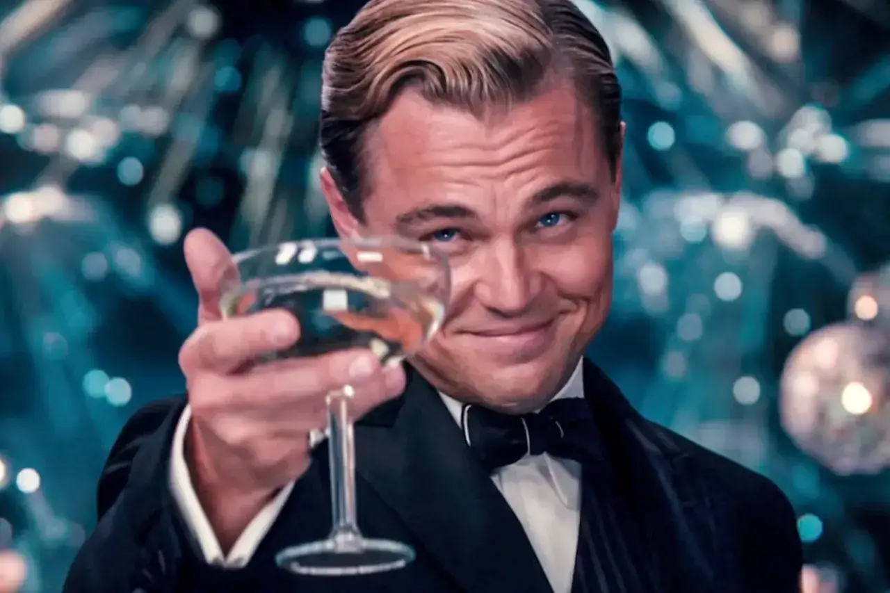 Jay Gatsby, wznosząc toast, uśmiecha się tajemniczo. To scena z filmu, która oddaje ducha 