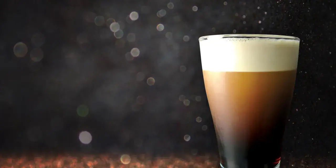 A velvety smooth nitro cold brew coffee with a creamy head, set against a dark, sparkling background.