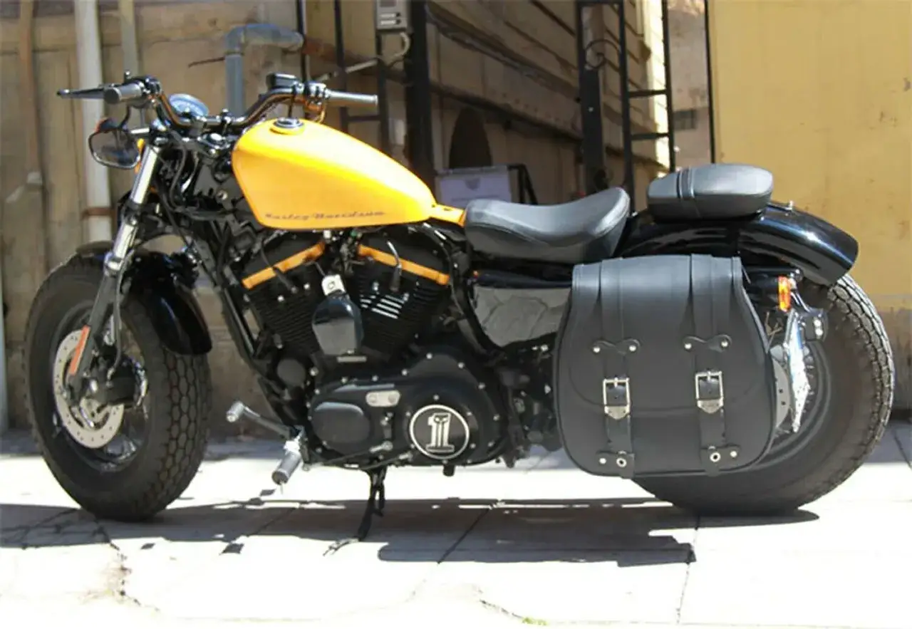 Harley-Davidson gialla con borse moto custom usate in pelle nera, pronte per il viaggio.