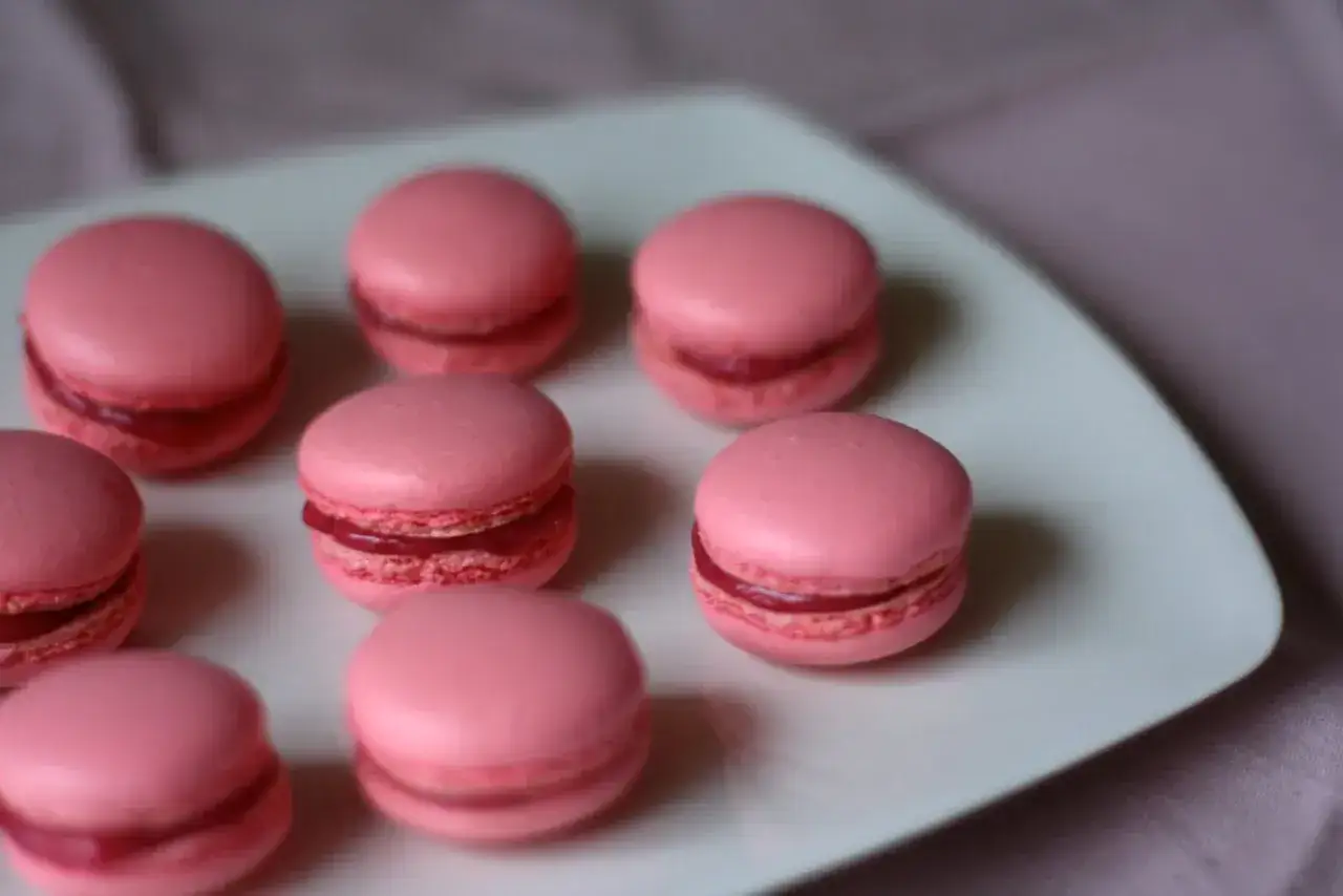 Rosa macarons med fyllning p&aring; en vit tallrik. Perfekt f&ouml;r ett macarons recept.