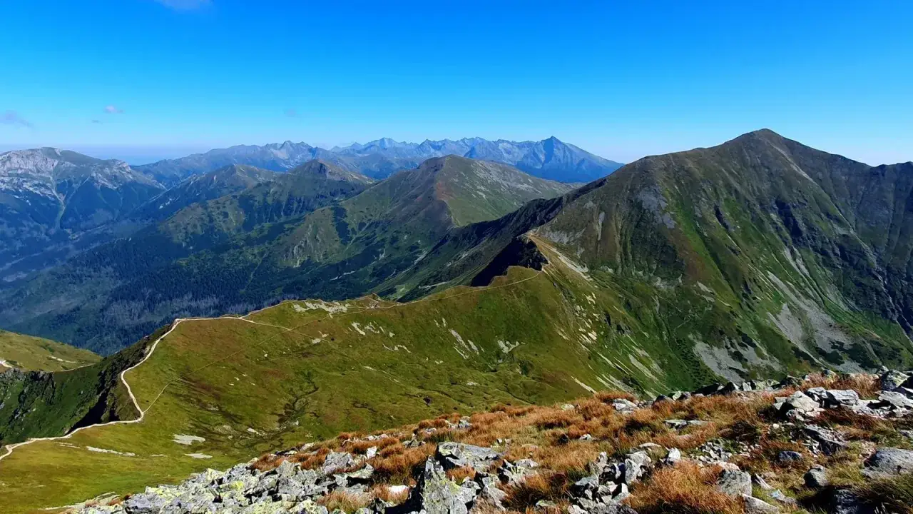 Widok na pasmo górskie z wyraźną ścieżką wijącą się po zboczu. W oddali widać kolejne szczyty Tatr, w tym Starorobociański Wierch.