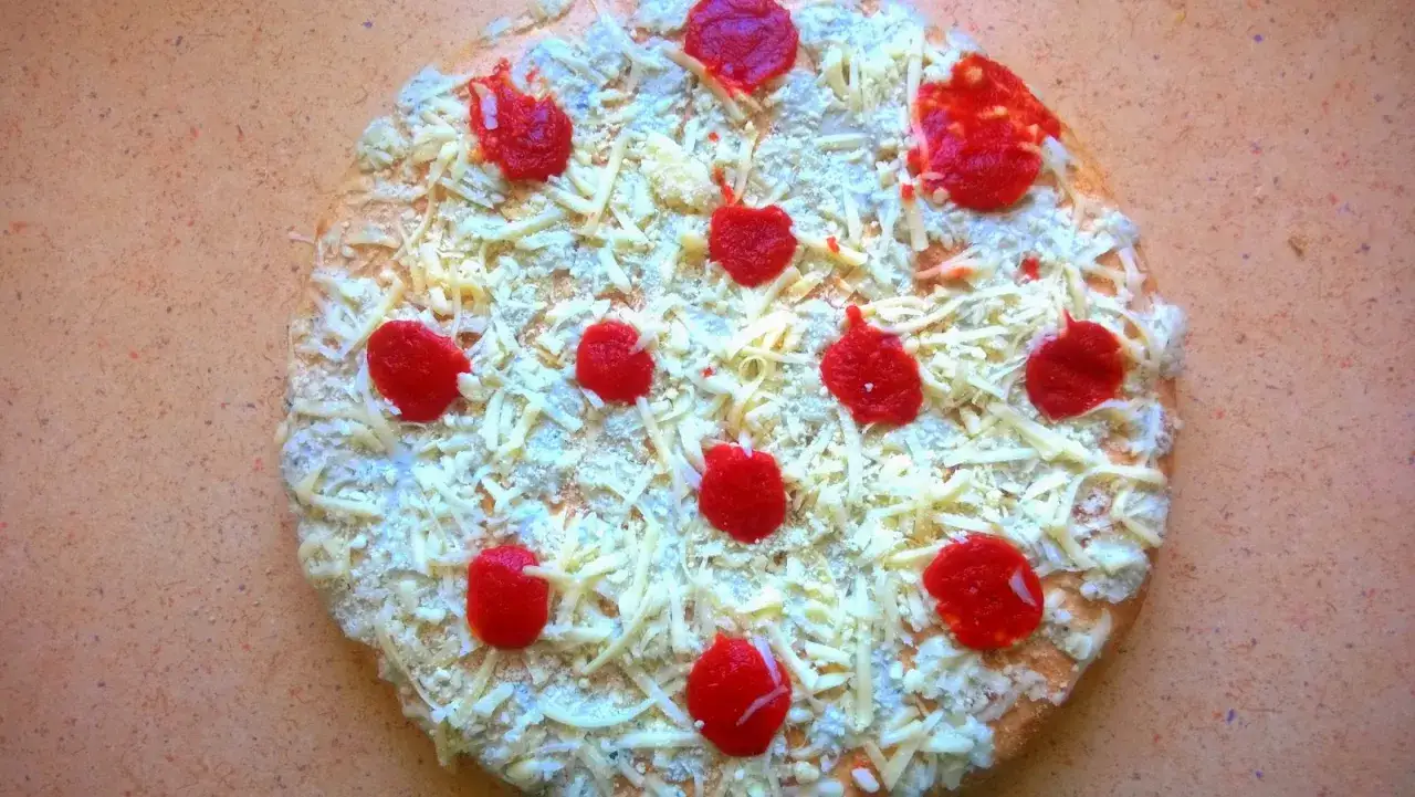 Pizza Giuseppe 4 sery, z sosem pomidorowym i mnóstwem sera, gotowa do pieczenia.
