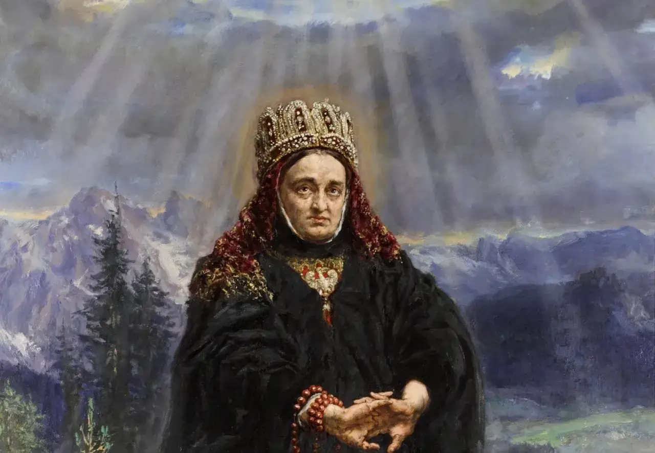 Św. Kinga patronka, w koronie i czarnym płaszczu, z różańcem w dłoniach, na tle gór i nieba.