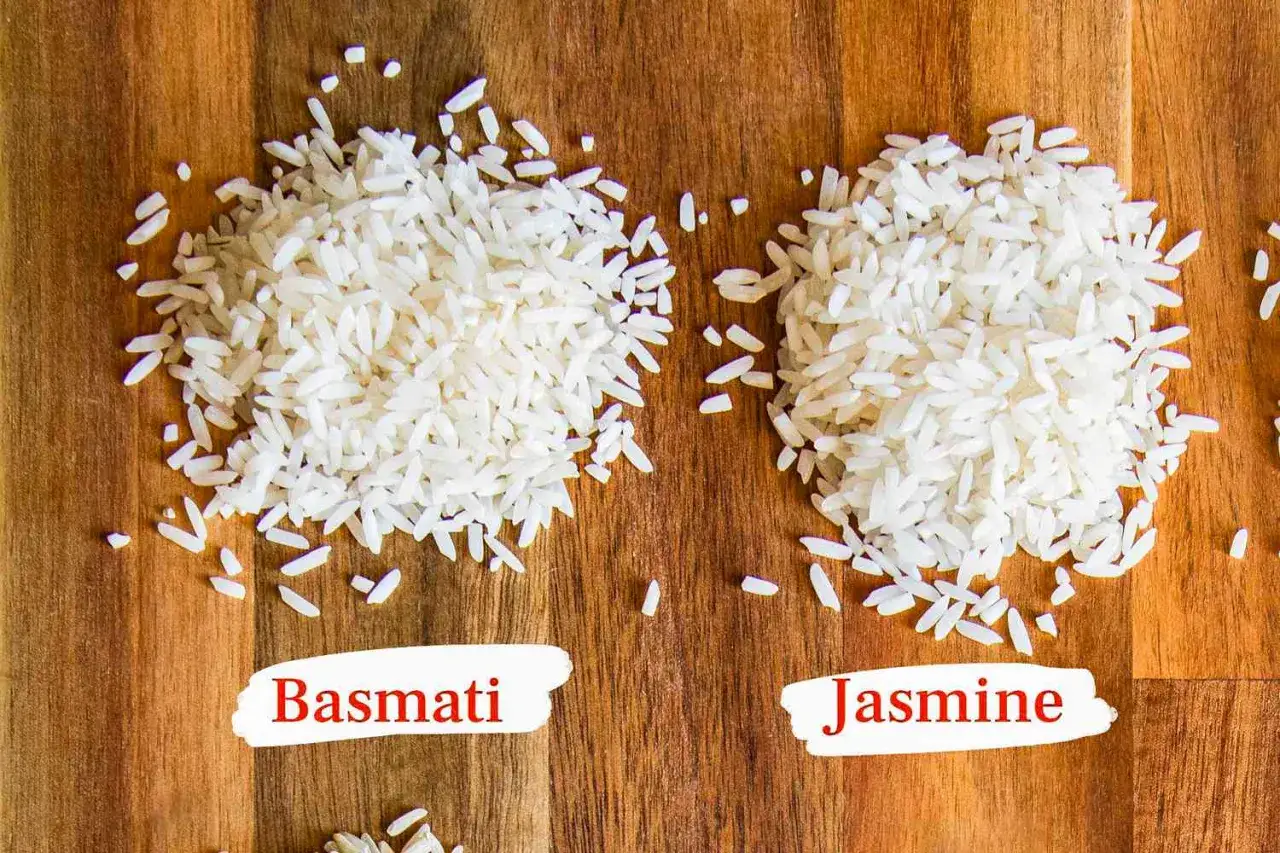 Zwei Haufen Reis, einer als Basmati, der andere als Jasmin Reis beschriftet, liegen auf einem Holztisch.