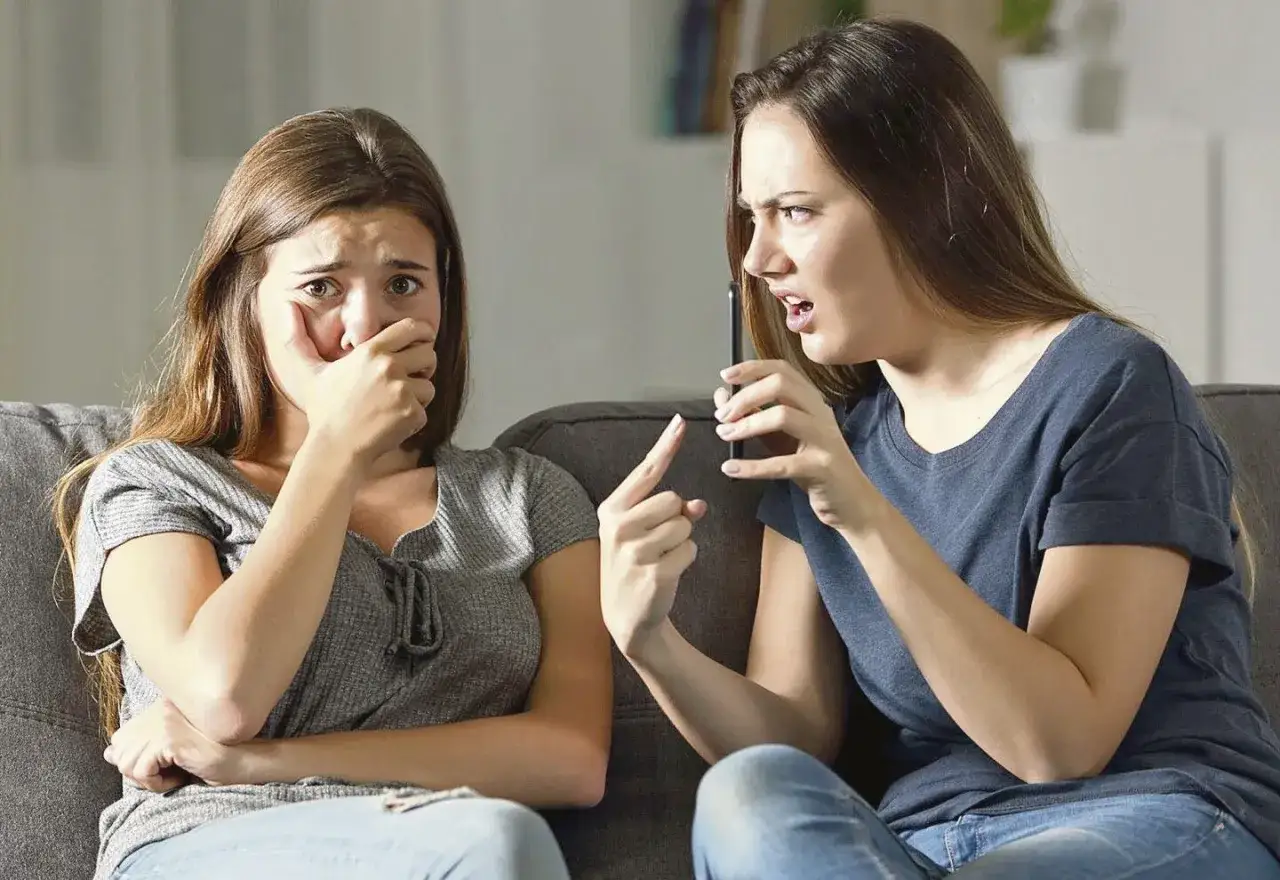 Una joven llora mientras otra le grita, sosteniendo un tel&eacute;fono. Un ejemplo de amistades t&oacute;xicas.
