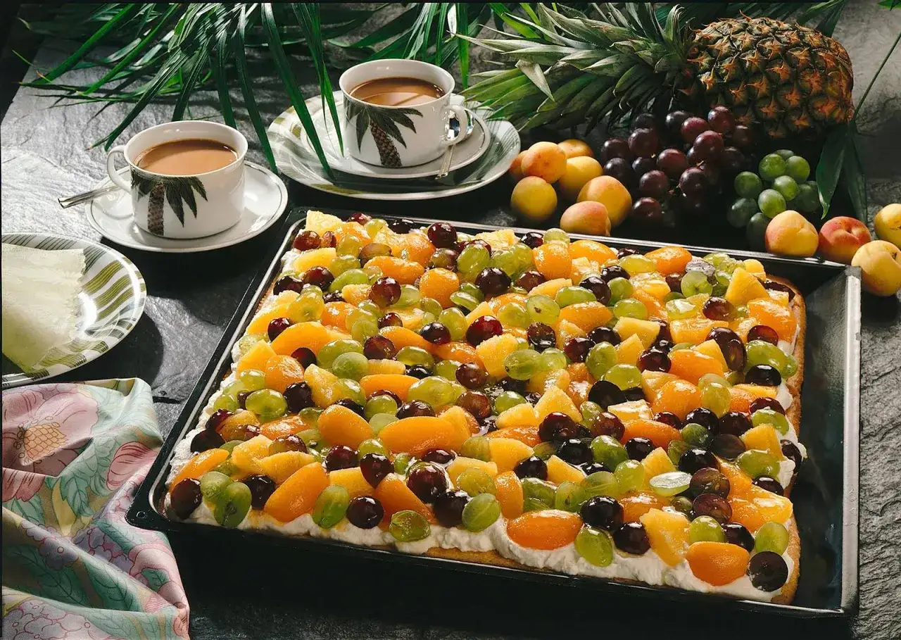 Bunter Obstkuchen mit Trauben, Pfirsichen und Mandarinen, inspiriert von Obstkuchen Rezepten. Dazu Kaffee und frische Früchte.