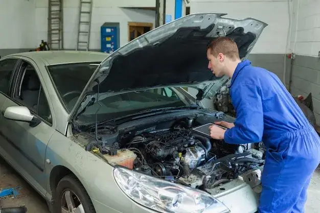 Samochód z otwartą maską, mechanik sprawdzający sprzęgło