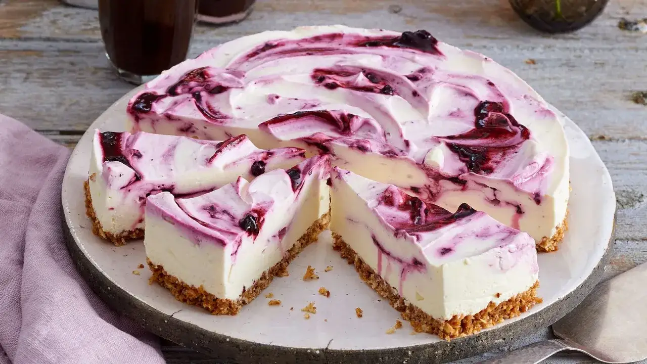 Cremiger Blueberry Cheesecake mit Swirls aus Blaubeersauce auf knusprigem Boden. Ein Genuss für jeden Anlass.