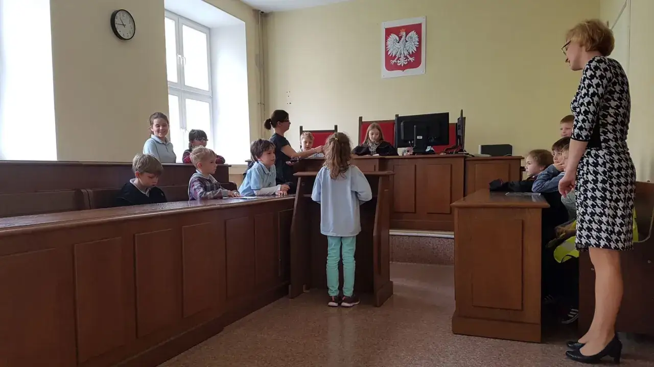 Dzieci w sali sądowej, symulacja procesu, gdzie omawiane jest ograniczenie praw rodzicielskich.