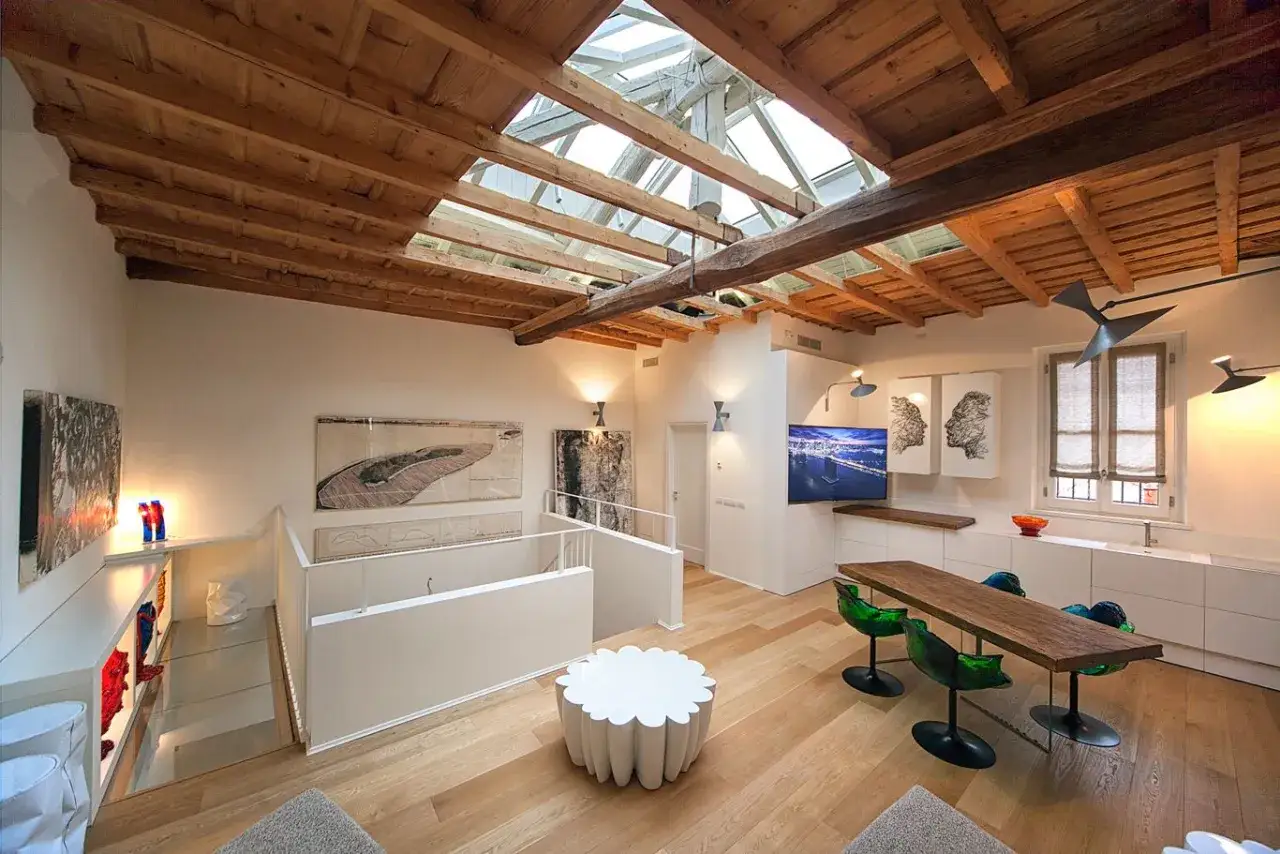 Soffitto a vista con travi in legno e lucernario, un'ispirazione per idee per rinnovare casa. Tavolo moderno, opere d'arte e arredi minimalisti.