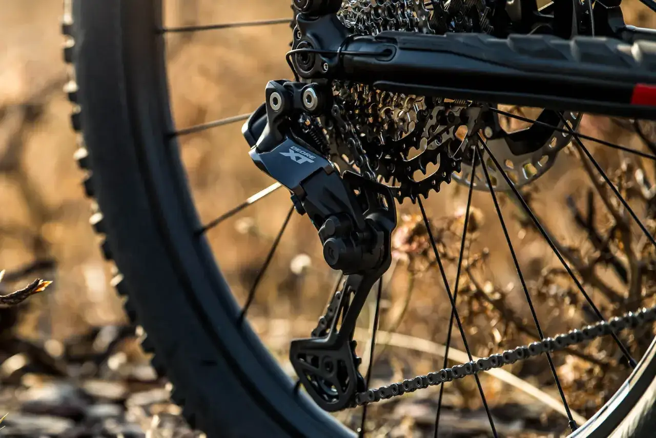 Close-up of a bicycle's rear derailleur, showcasing the Shimano Deore XT component, hinting at the future of shimano wireless shifting technology.