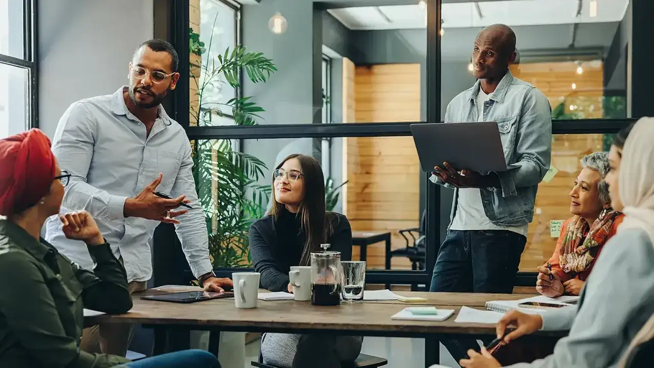 Ein diverses Team bespricht Ideen. M&auml;nner und Frauen unterschiedlicher Herkunft und Altersgruppen arbeiten zusammen. Tolle diversity beispiele!