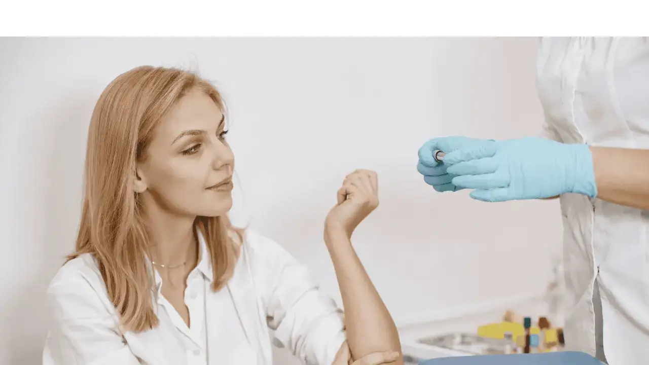 Kvinna förbereder sig för ett b12 test. En sjuksköterska i blå handskar håller en provrör.