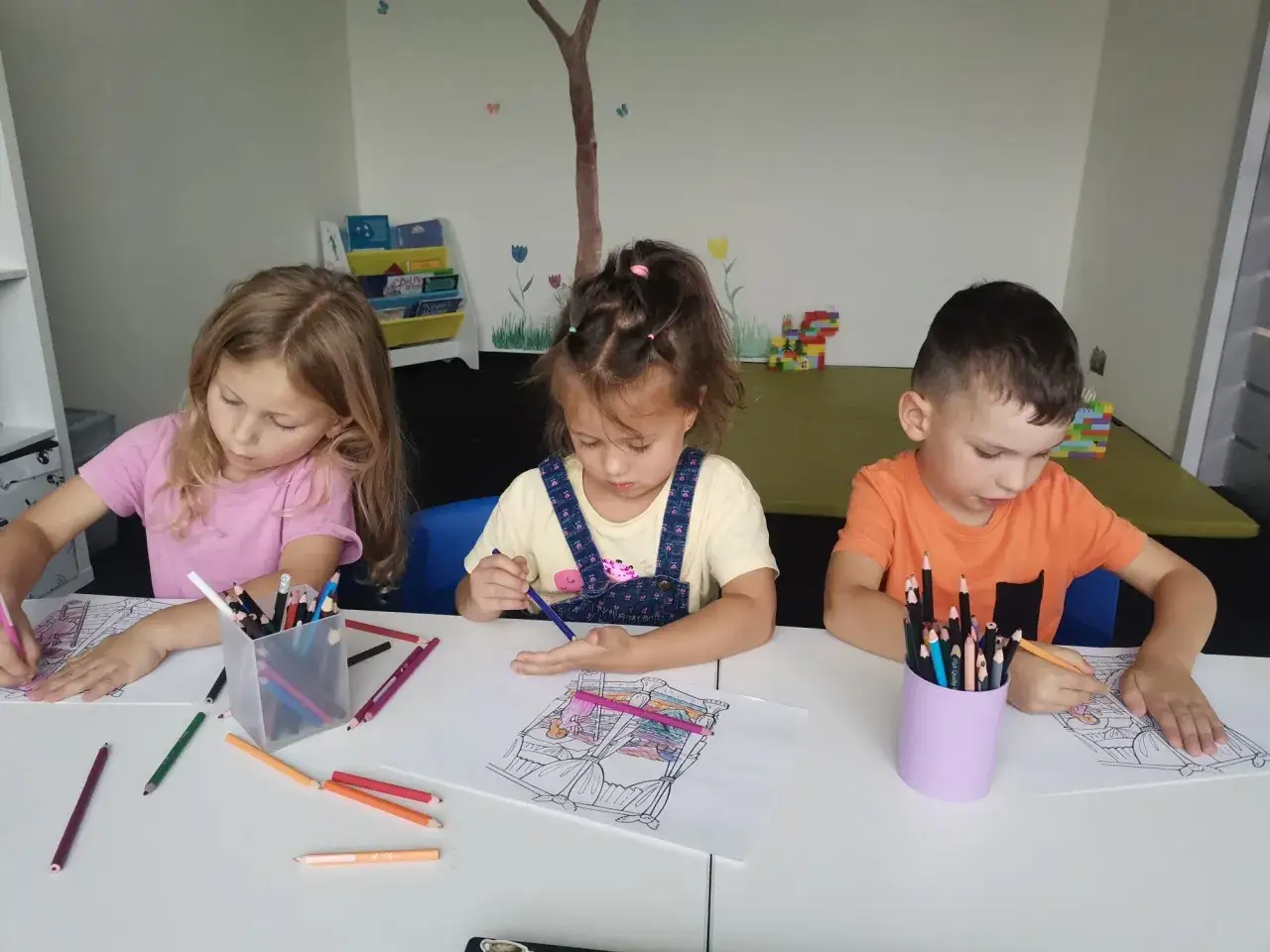 Dzieci w różnym wieku do szkoły, skupione na kolorowankach.