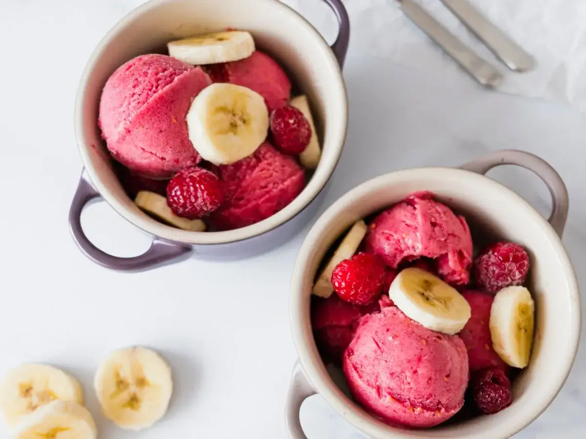 Zwei Schalen mit leckerem Nicecream-Rezept, garniert mit Himbeeren und Bananenscheiben. Ein erfrischender Genuss!