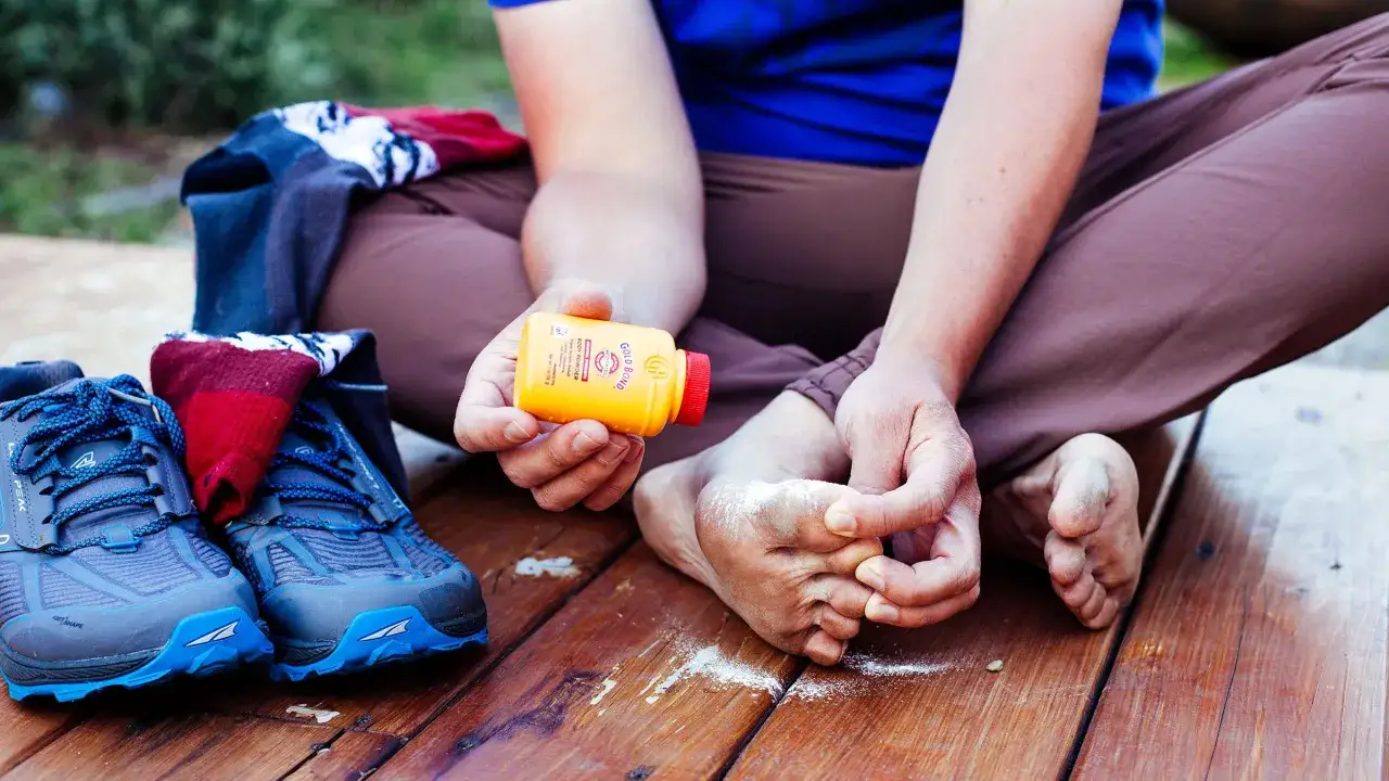 Preparing to wear hiking boots: applying powder to feet for comfort.