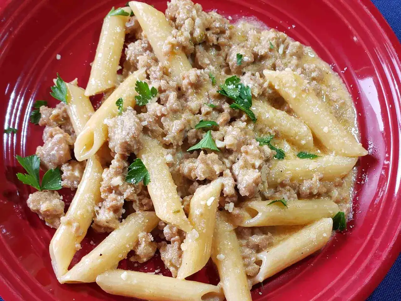En portion salsicciapasta Benjamin, med penne och en kr&auml;mig k&ouml;ttf&auml;rss&aring;s, toppad med persilja och parmesan.