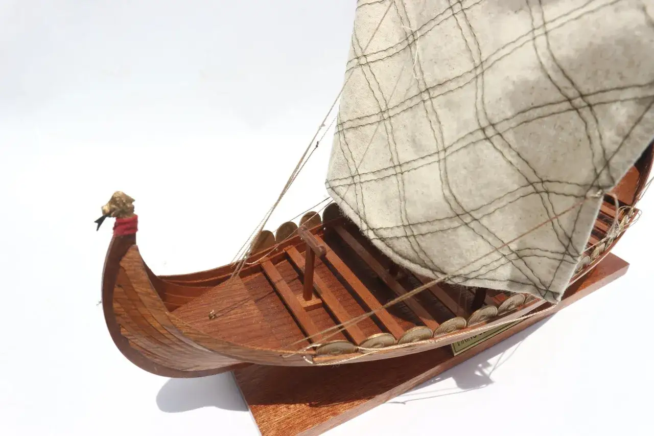 Ein detailgetreues Modell eines Wikinger-Boots mit Drachenkopf am Bug und Segel.