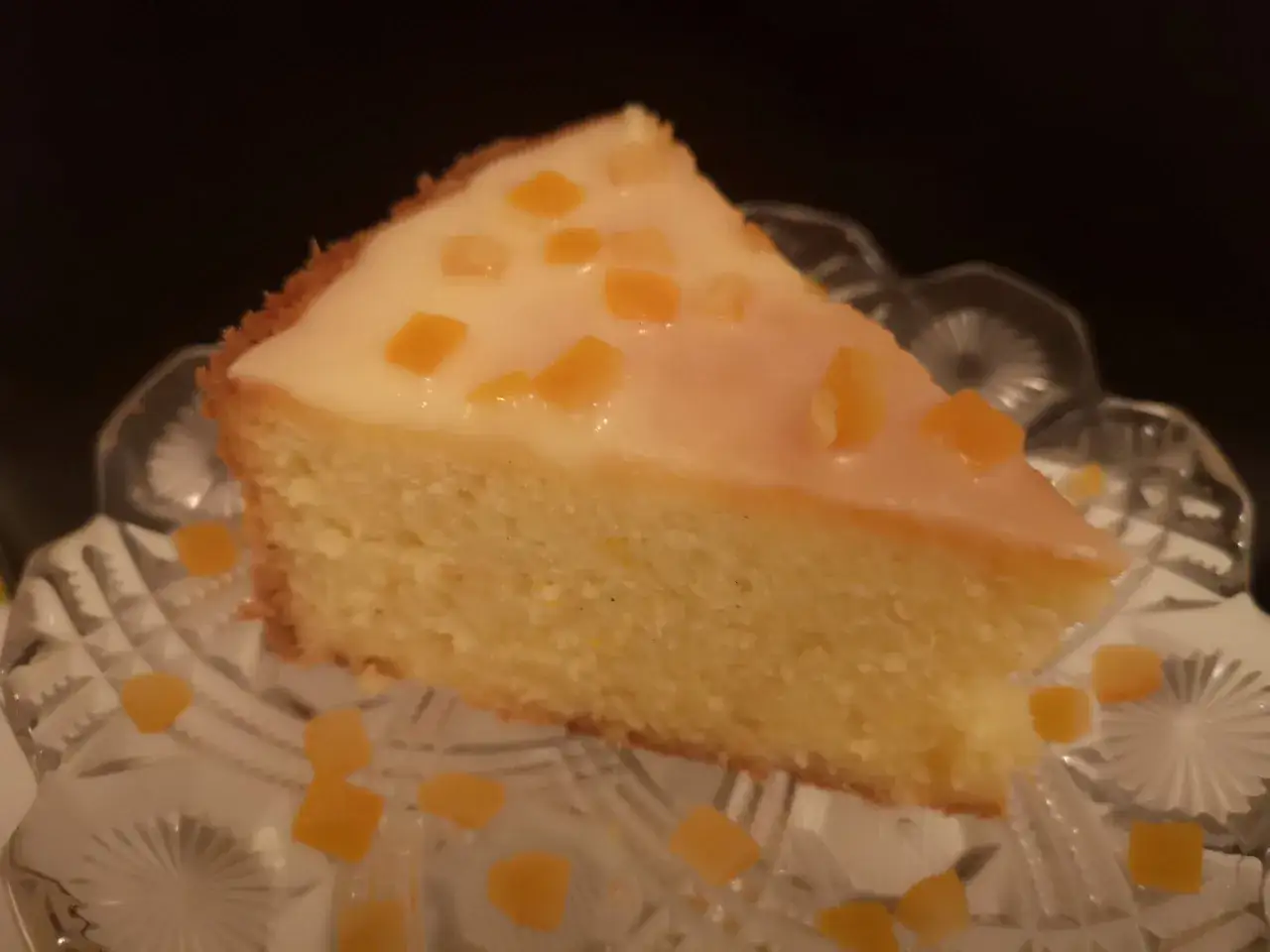 En bit saftig ambrosiakaka i långpanna, toppad med glasyr och kanderad frukt, serverad på ett vackert fat.