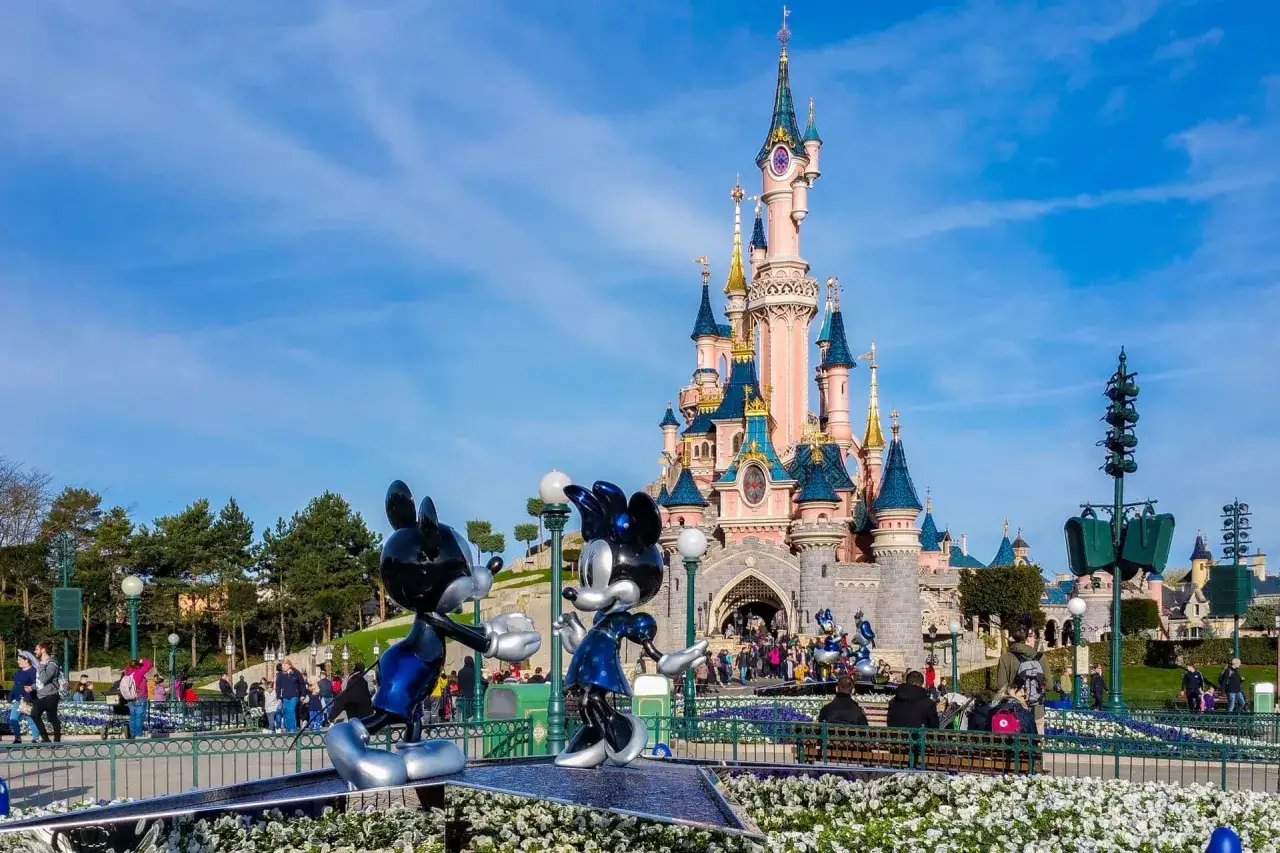Myszka Miki i Minnie witają gości w Disneylandzie w Paryżu, przed bajkowym zamkiem.