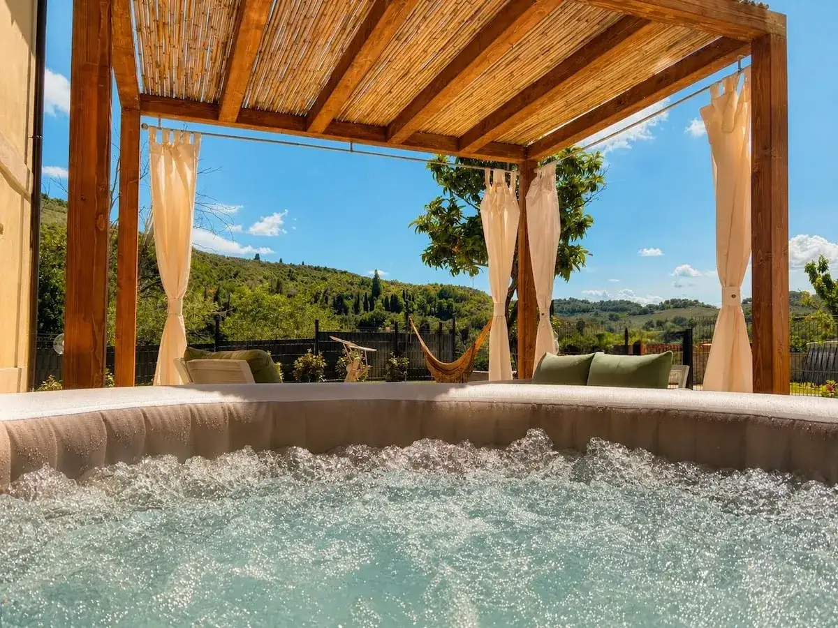 Un idromassaggio sotto un pergolato di bamb&ugrave;, con vista su colline verdi e un cielo azzurro. Un luogo perfetto per rilassarsi e godersi gli **aspri terme**.