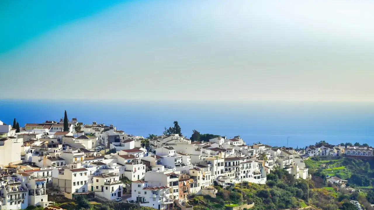 Un pintoresco pueblo blanco en una colina, con el mar azul al fondo. Podría ser el pueblo más bonito de Andalucía.