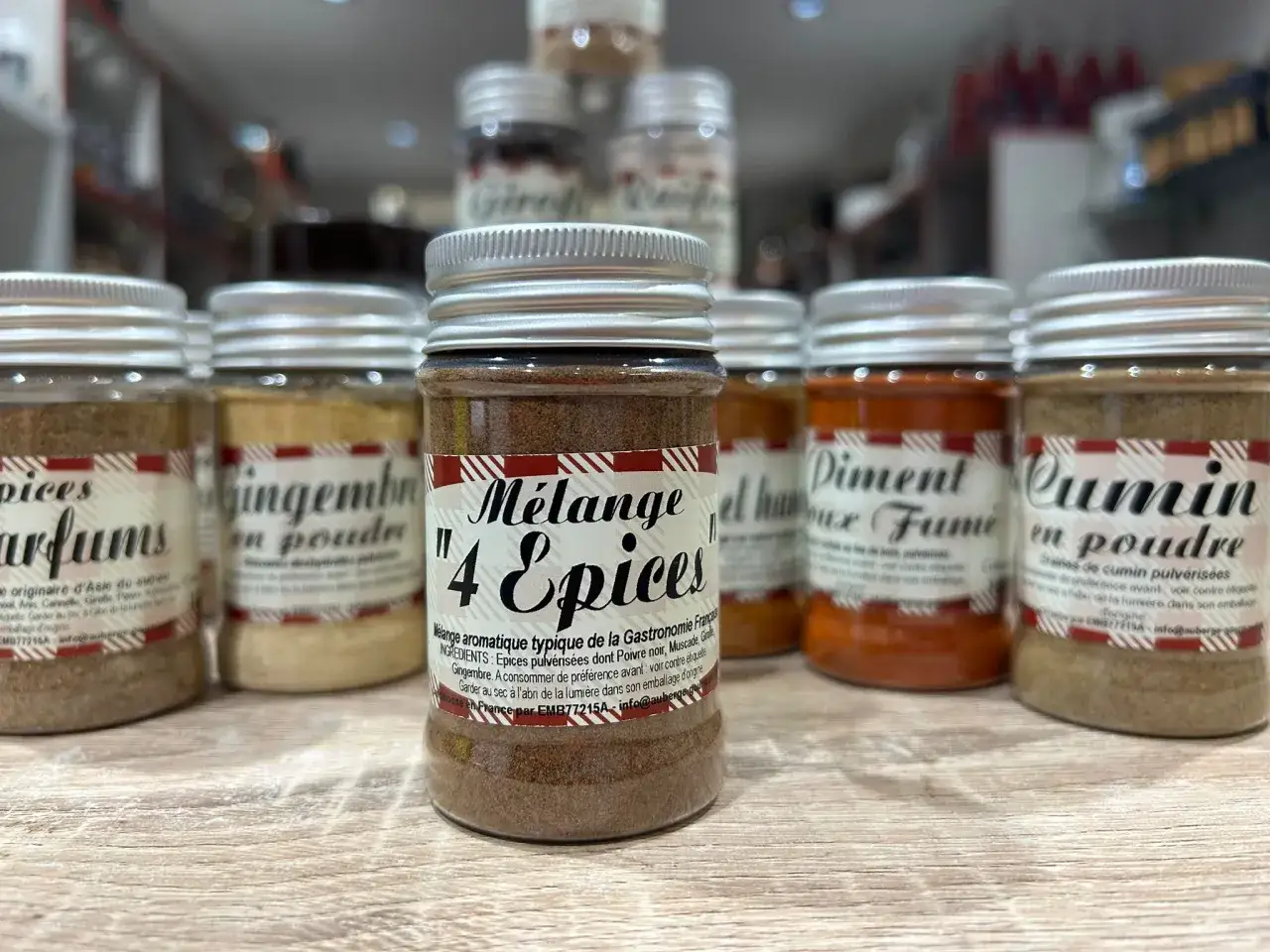Un pot de m&eacute;lange 4 &eacute;pices, typique de la gastronomie fran&ccedil;aise, se trouve au centre d'une &eacute;tag&egrave;re remplie d'autres &eacute;pices en poudre.