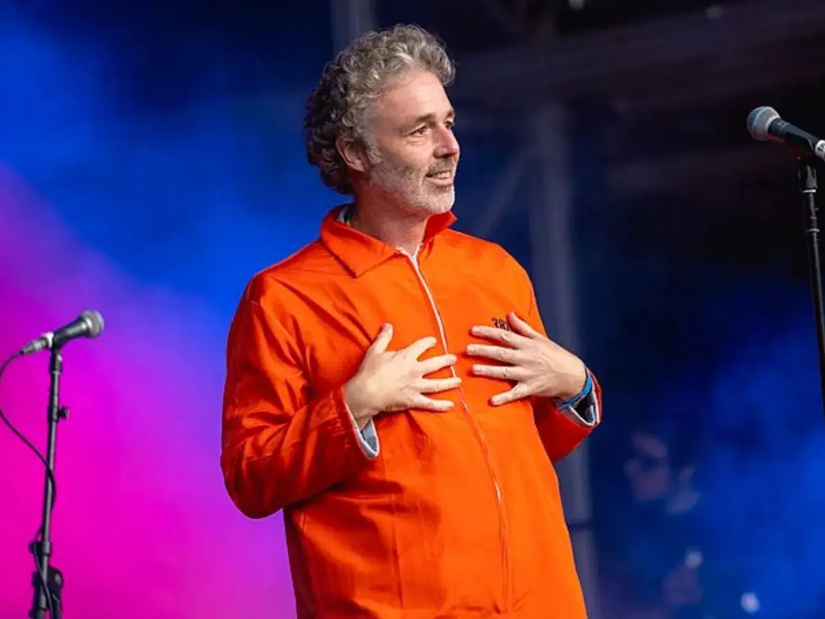 Baxter Dury, jak Aylesbury boy, w pomarańczowym kombinezonie na scenie.