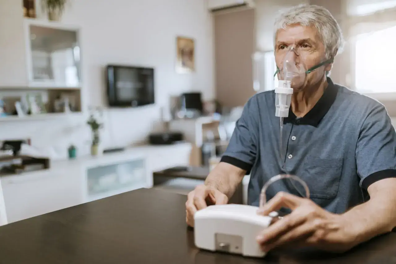 &Auml;lterer Mann mit Inhalatormaske, der die Behandlung f&uuml;r Asthma im Alter durchf&uuml;hrt.