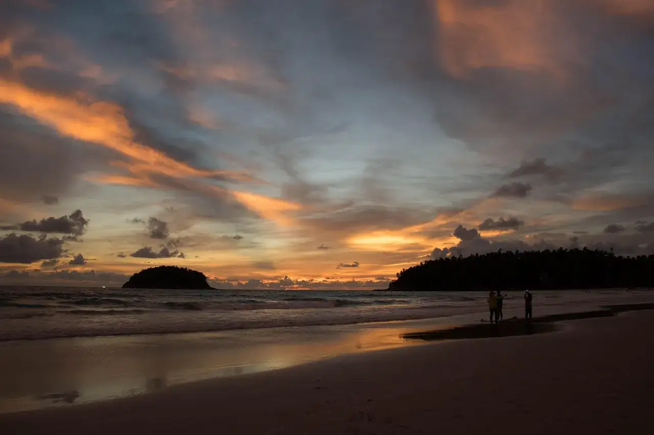 Zach&oacute;d słońca na plaży na Phuket w grudniu. Piękna pogoda, niebo w odcieniach pomarańczy i szarości.
