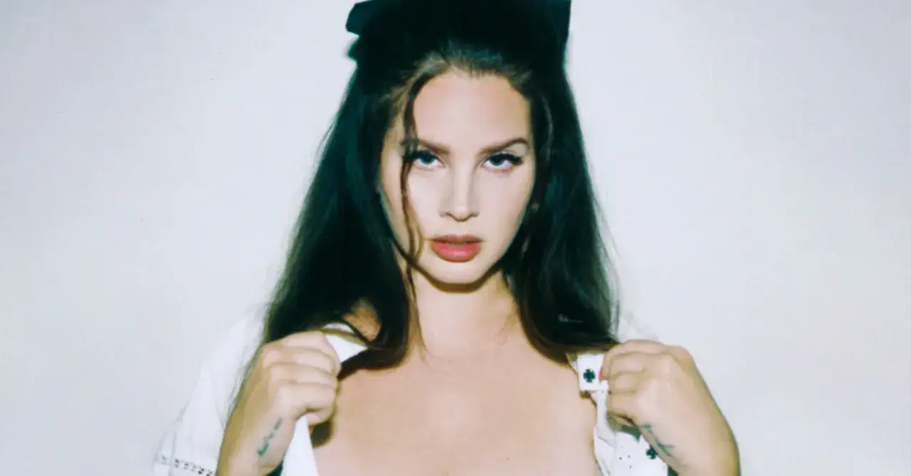 Lana Del Rey z czarną kokardką we włosach, w białej bluzce, wygląda jakby czekała na nowy album.