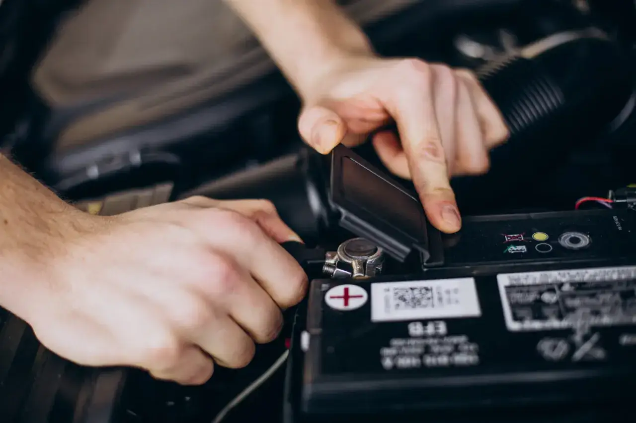 Dłonie podłączają ładowarkę do akumulatora motocyklowego 12V. Dowiedz się, jak długo ładować akumulator motocyklowy 12v.
