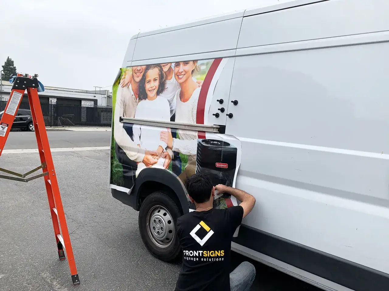 A worker applies a family photo wrap to a white truck, showcasing how to wrap a truck for advertising.