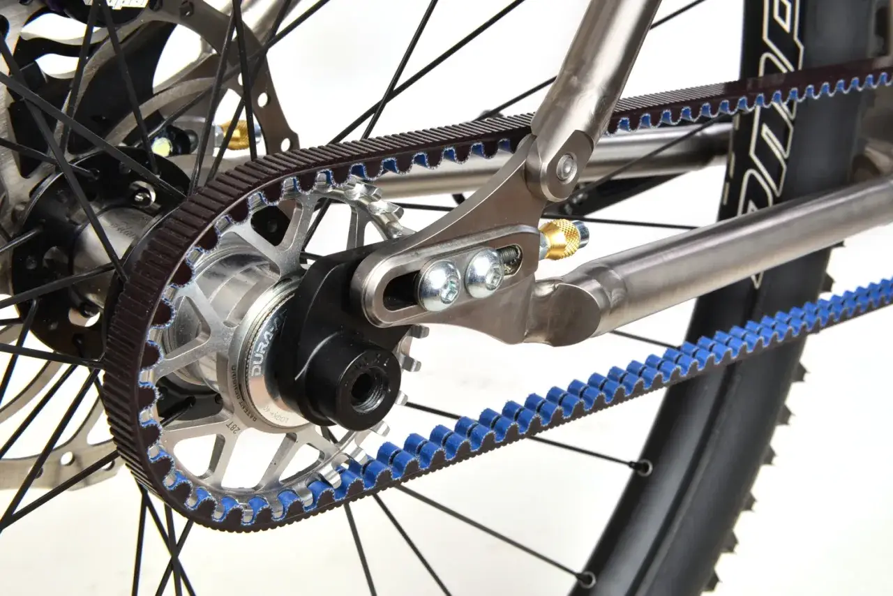 Detailaufnahme einer Fahrrad-Pinion-Schaltung mit Zahnriemenantrieb. Der Riemen läuft über ein Ritzel am Hinterrad und eine weitere Scheibe.