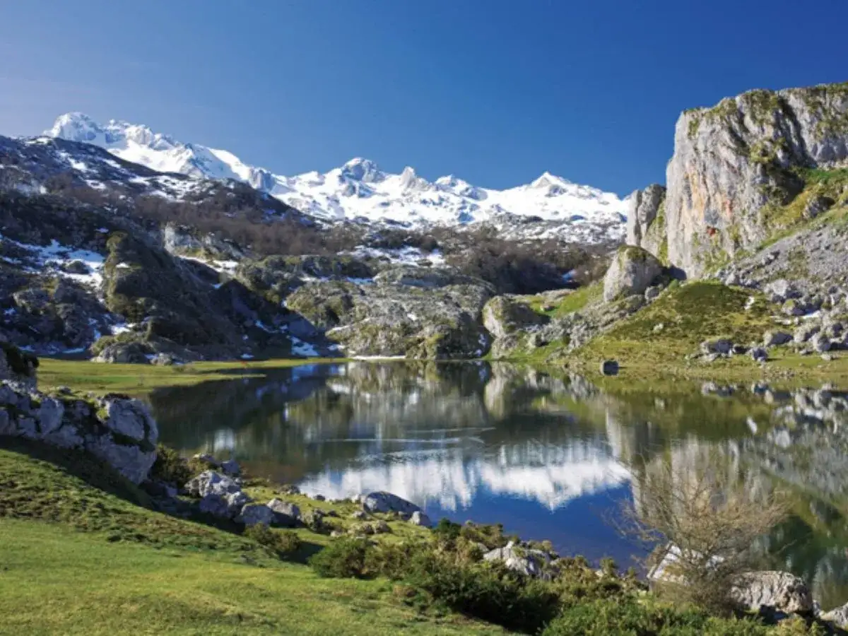 Lago sereno reflejando picos nevados en uno de los parques nacionales de España.