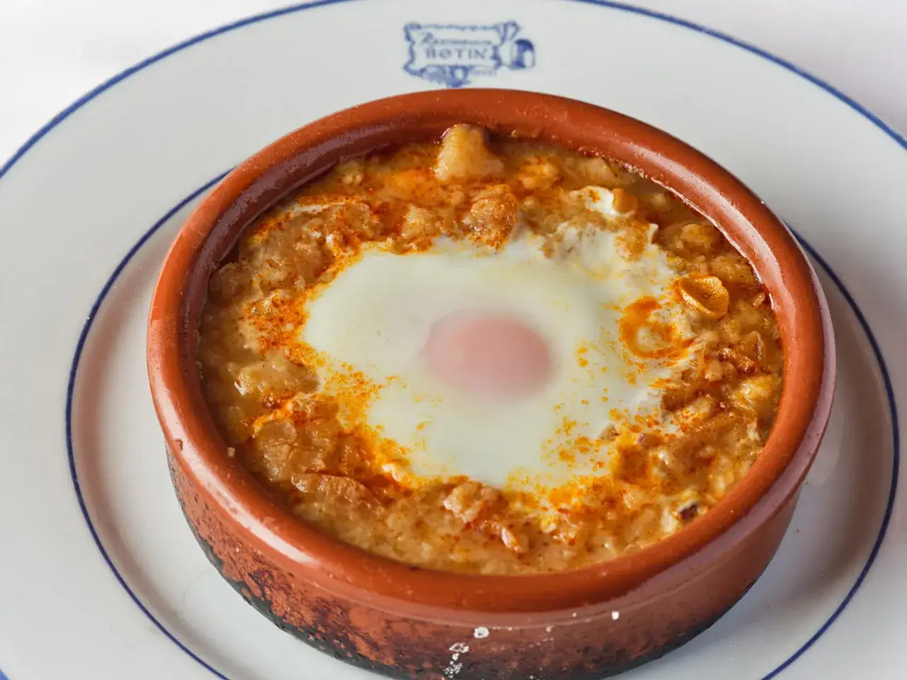 Un huevo escalfado sobre una base cremosa con piment&oacute;n, un plato del sobrino de Bot&iacute;n men&uacute;.
