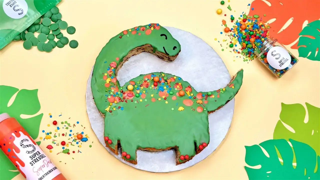 Gr&uuml;ne Dinosaurier Torte selber machen mit bunten Streuseln und Schokodrops. Ein Spa&szlig; f&uuml;r kleine und gro&szlig;e Dino-Fans!