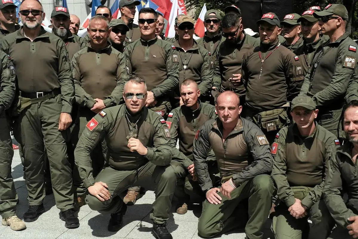 Grupa mężczyzn w mundurach, niekt&oacute;rzy z naszywkami BPG. Jeden z nich trzyma duży, brązowy broń.