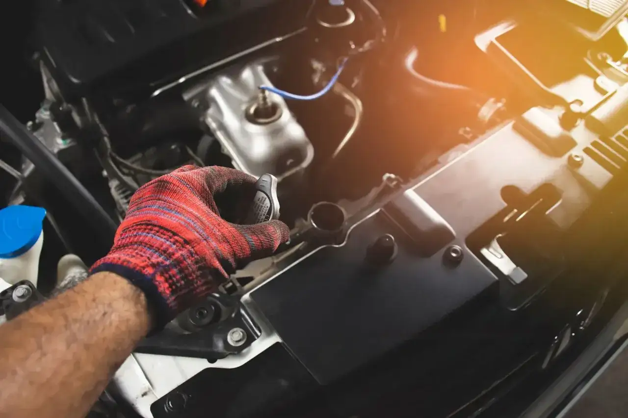 Rękawica mechanika odkręca korek chłodnicy, sugerując duży wyciek płynu chłodniczego.