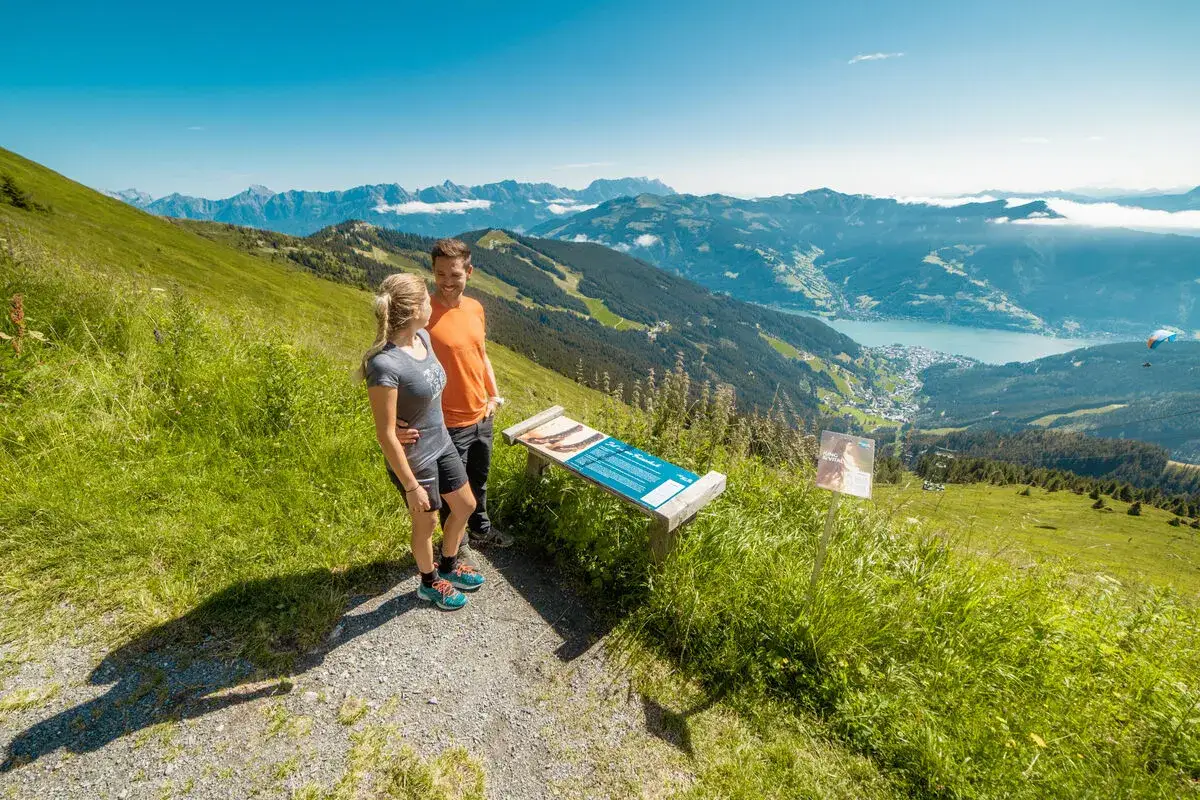 Ein Paar genie&szlig;t die Aussicht beim Zell am See Wandern. Der See und die Berge sind im Hintergrund zu sehen.
