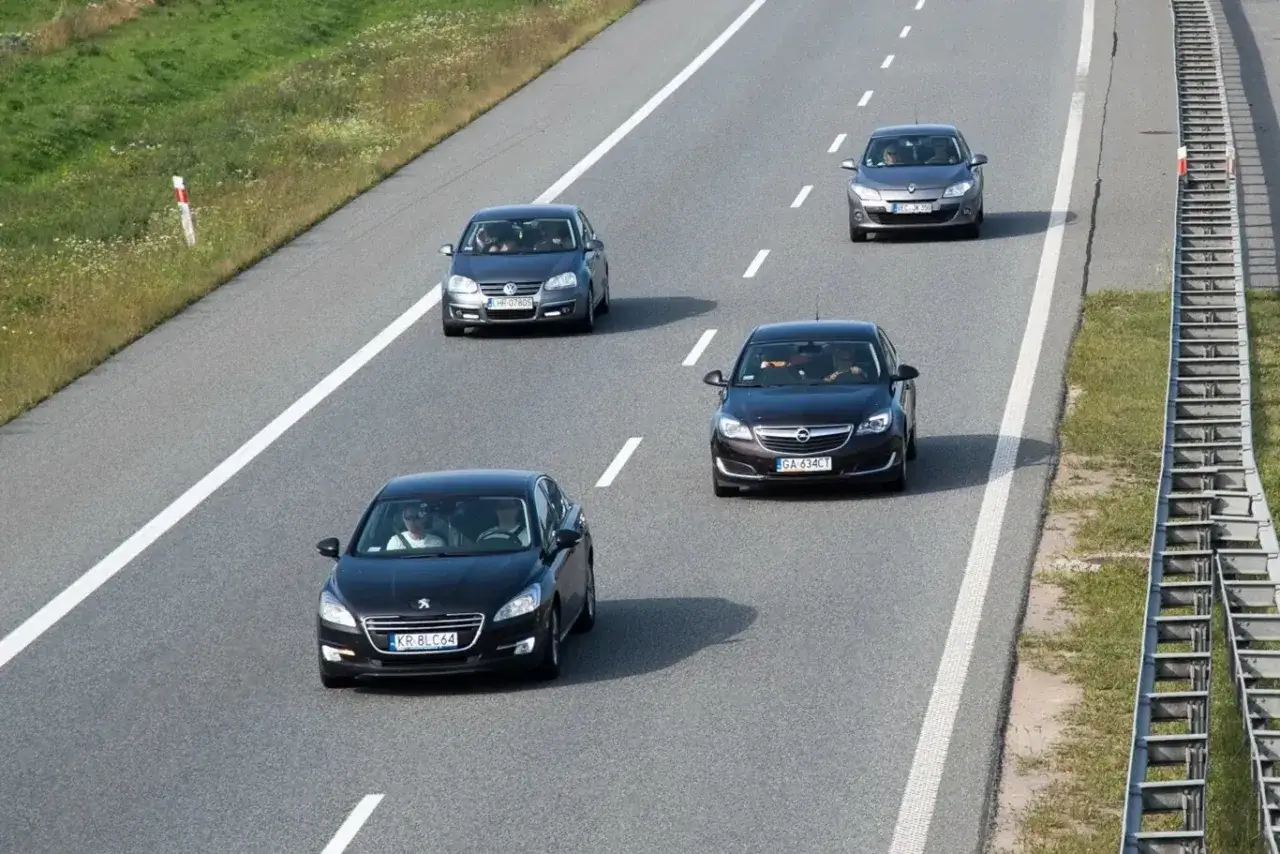 Czarny Peugeot wyprzedza z prawej strony na autostradzie inne samochody.