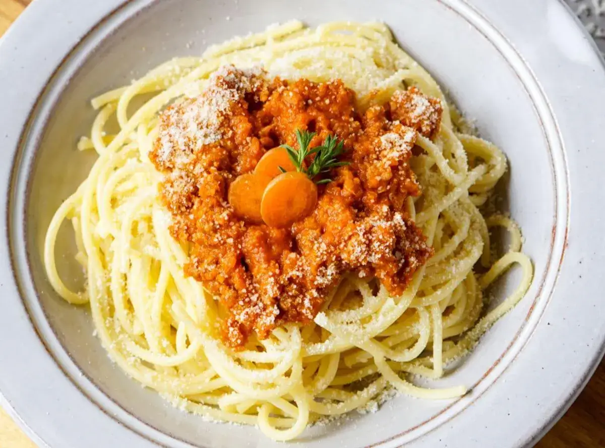 Spaghetti Bolognese, zubereitet im Thermomix, mit Karottenscheiben und Petersilie garniert.