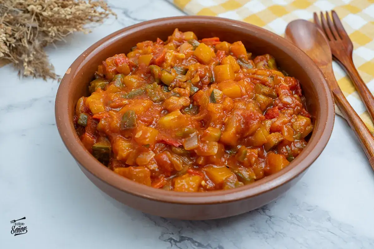 Un tazón de bonito con pisto, un plato tradicional español lleno de verduras y sabor.